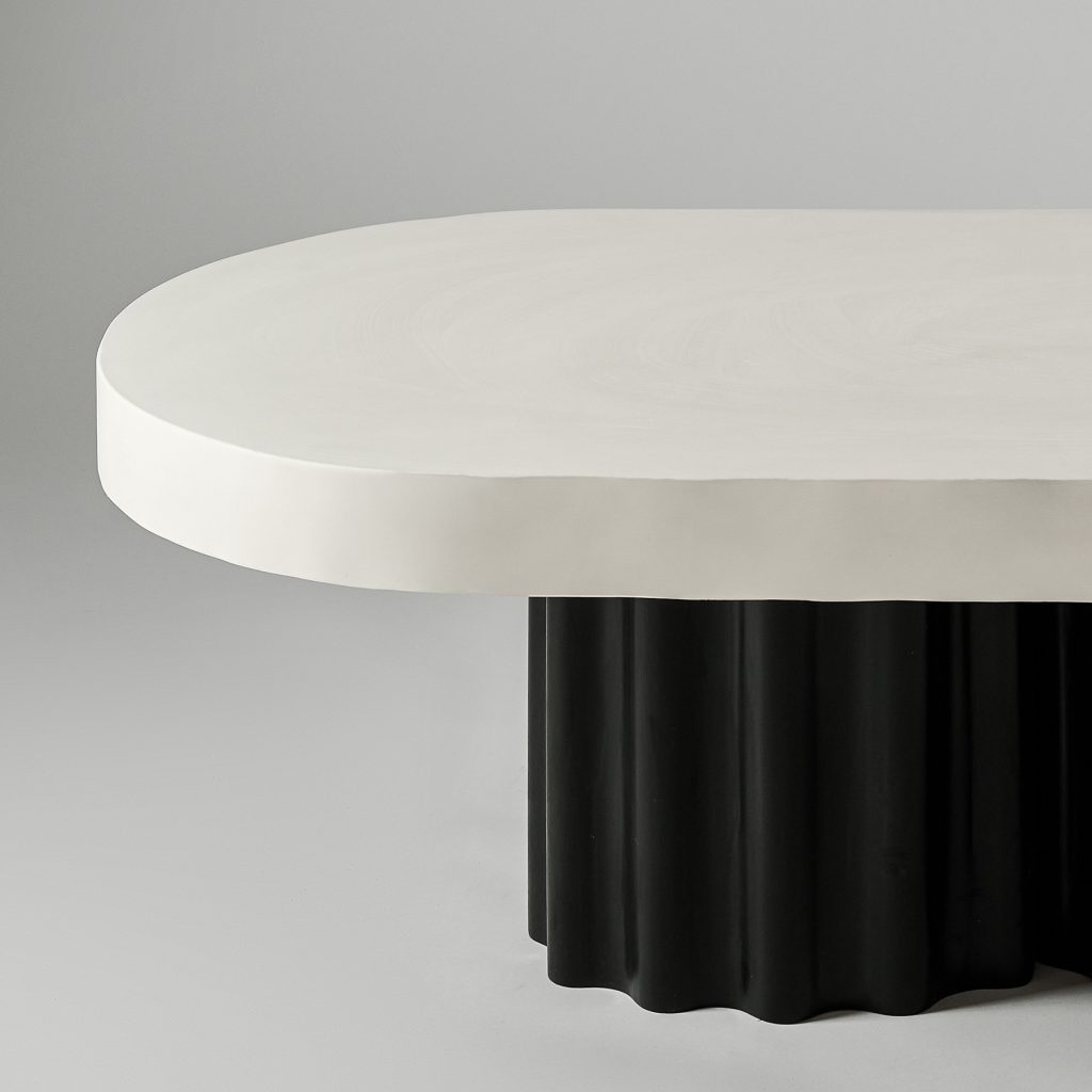 Owalny stolik z białym blatem i czarną nogą